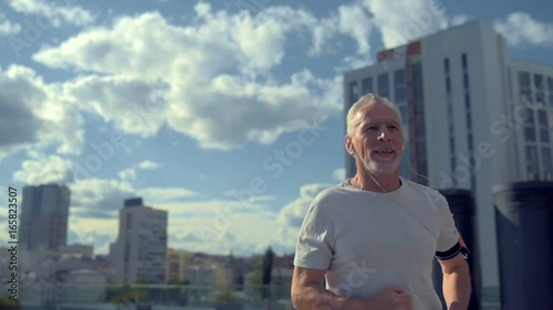 Cheerful senior man running in the urban surrounding