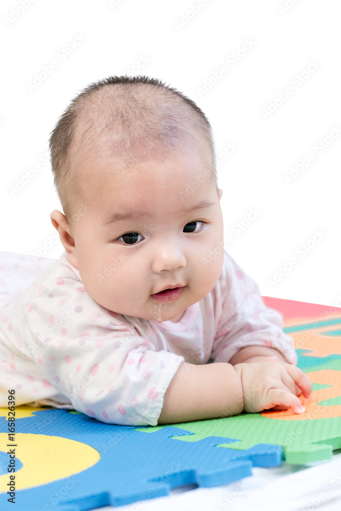 Portrait of a little adorable newborn infant baby girl with saliva lying on the tummy on colorful eva foam and looking in camera indoors. Isolated on white background with copy space and clipping path Portrait of a little adorable newborn infant baby girl with saliva lying on the tummy on colorful eva foam and looking in camera indoors. Isolated on white background with copy space and clipping path