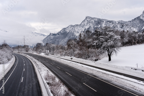 view of a highway or autobahn in Switzerland in deep winter with snowy landscape and mountains photo