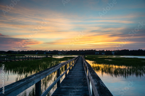 boardwalk leading into tidal basin of a barrier island filled with marsh grass under a beautiful sky at sunset in South Carolina photo