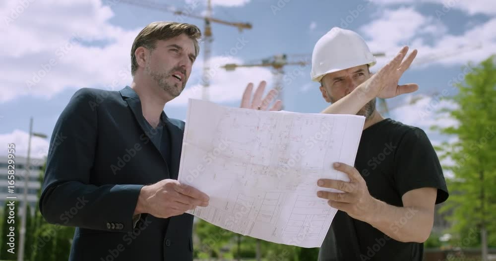 Attractive architect and construction manager discussing constructions plans outside