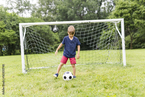 Young Boy with football on a field having fun photo