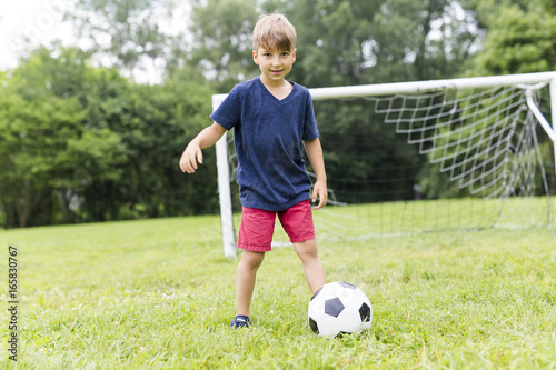 Young Boy with football on a field having fun