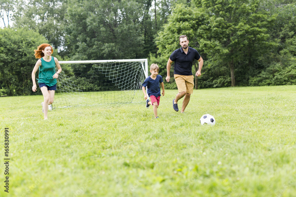 Cheerful family playing football in a park Cheerful family playing football in a park