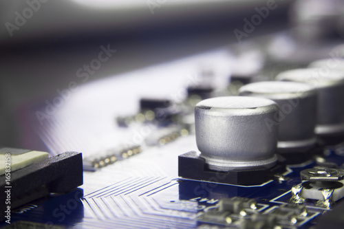 Close up macro of aluminum electrolytic capacitors installed on the motherboard and electronic component with selective focus. Electronics part concept. photo