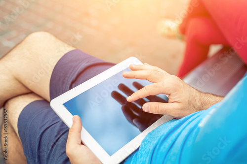 Man sitting on a bench and using a digital tablet