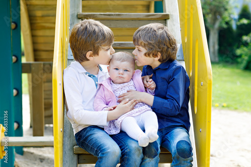 Two little happy kid boys with newborn baby girl, cute sister.