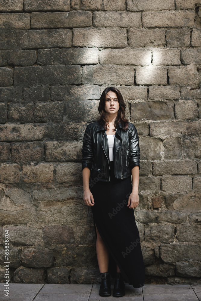 Portrait of young modern woman wearing leather jacket in front old stone wall. Portrait of young modern woman wearing leather jacket in front old stone wall.