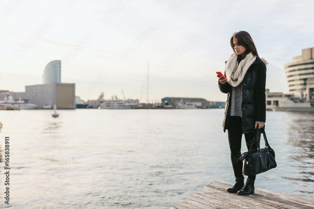 Back view of young woman with winter clothes standing on the dock. Back view of young woman with winter clothes standing on the dock.