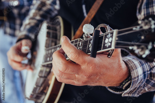 Musician's hands playing a banjo at a festival outdoors photo