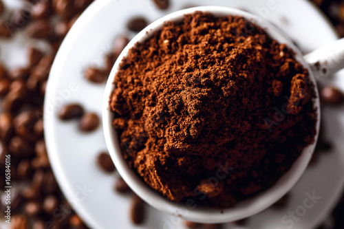Close up of a coffee cup with coffee grounds and coffee beans around