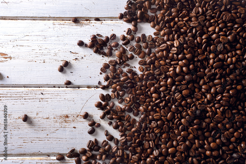Roasted coffee beans over a white wood table Roasted coffee beans over a white wood table