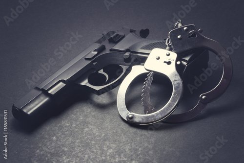 Photo handgun with handcuffs on dark background, crime concept, law enforcement