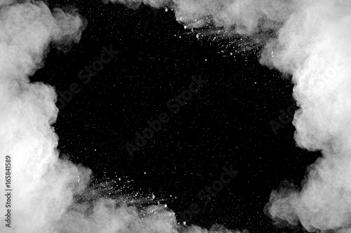 Freeze motion of white dust explosion on black background. Stopping the movement of white powder on dark background. Explosive powder white on black background.