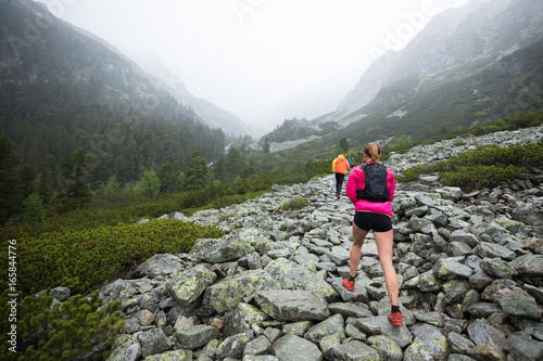 woman hiking on high mountains outdoor track in bad weather with fog and rain