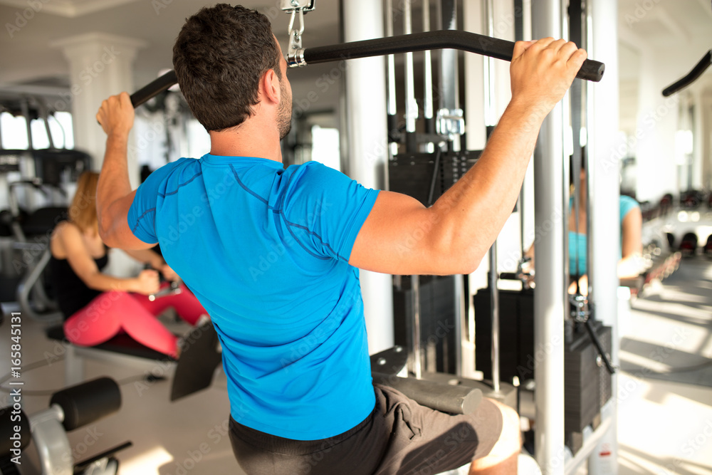 Fit man exercising at the gym on a machine Fit man exercising at the gym on a machine