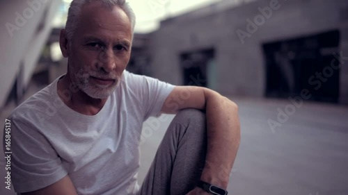 Senior tired man resting after sport exercises outdoors