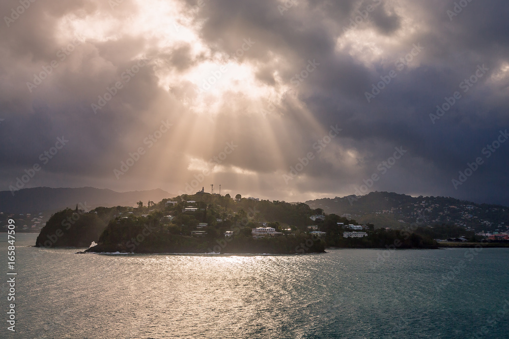 A dramatic set of clouds, at sunset, drifting over the tropical waters of the Caribbean Sea are lit by the last moments of daylight.