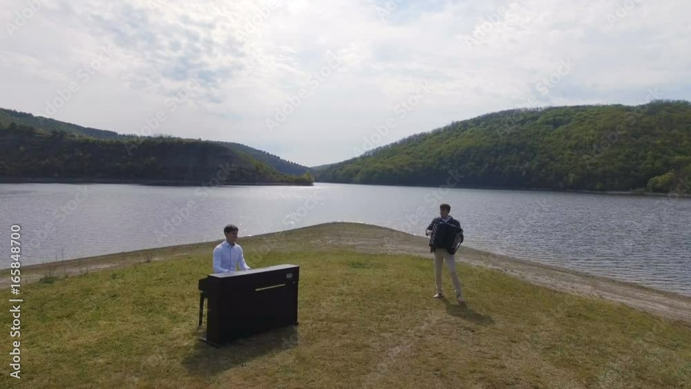 Aerial view. Two musicians Pianist and accordionist playing on the island Aerial view. Two musicians Pianist and accordionist playing on the island