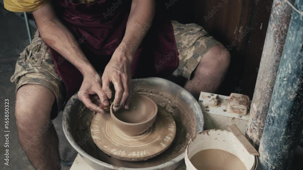 Potter shapes the clay product with pottery tools on the potter's wheel, top view, toned cinematic, craft factory authentic Potter shapes the clay product with pottery tools on the potter's wheel, top view, toned cinematic, craft factory authentic