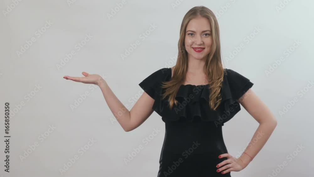 Young girl in black dress demonstrates a product at white background