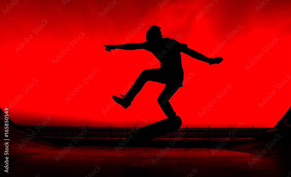 Silhouette of a young skater on a bright red background