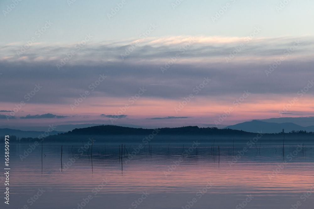 An island on a lake at dusk, with beautiful and warm sky reflections on water