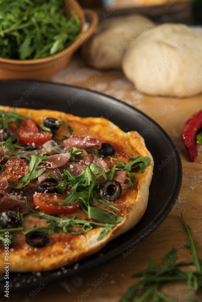 Traditional pizza with prosciutto and arugula Traditional pizza with prosciutto and arugula