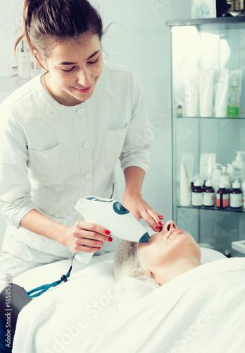 Aged woman making beauty procedures for face in spa salon