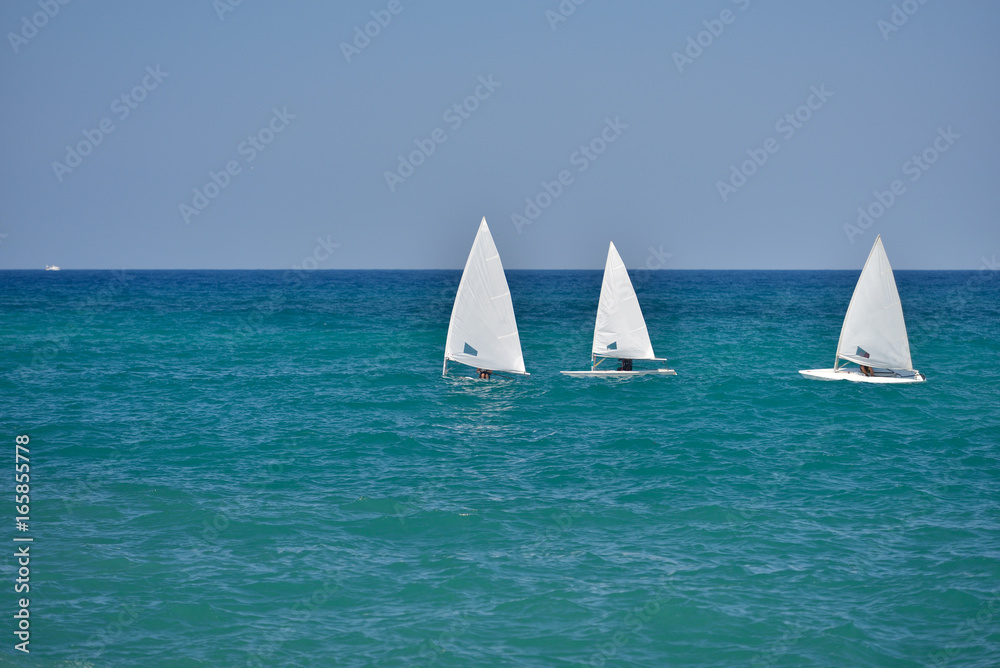 Small sailboats sailing in the calm waters of the Adriatic Sea, south Italy