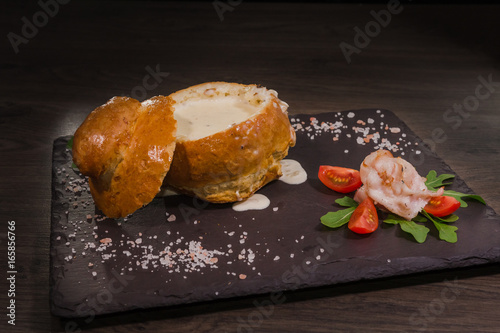 Fresh pea soup in a Bread Bowl, on a wooden board with salt and papper photo