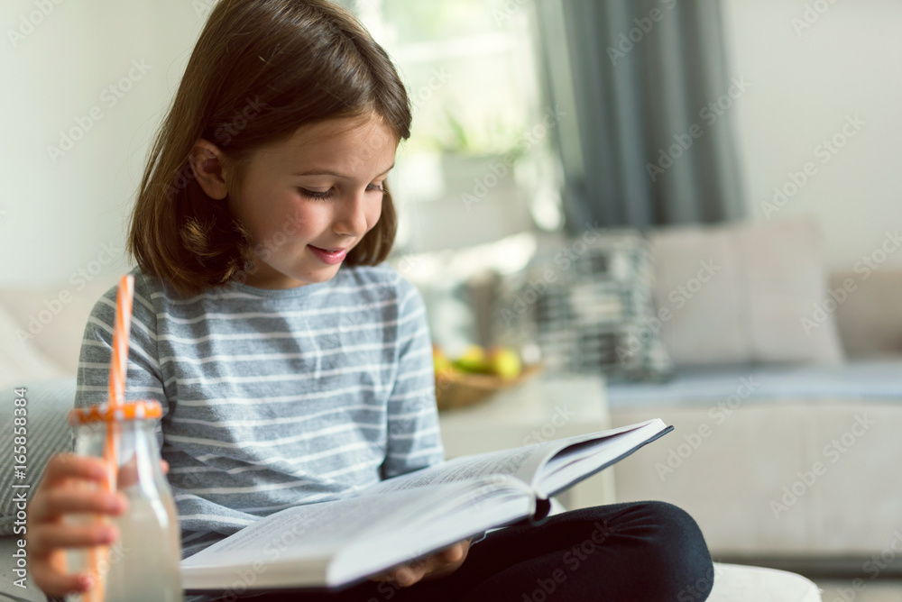 Cute young girl reading exciting book and drinking lemonade at home Cute young girl reading exciting book and drinking lemonade at home