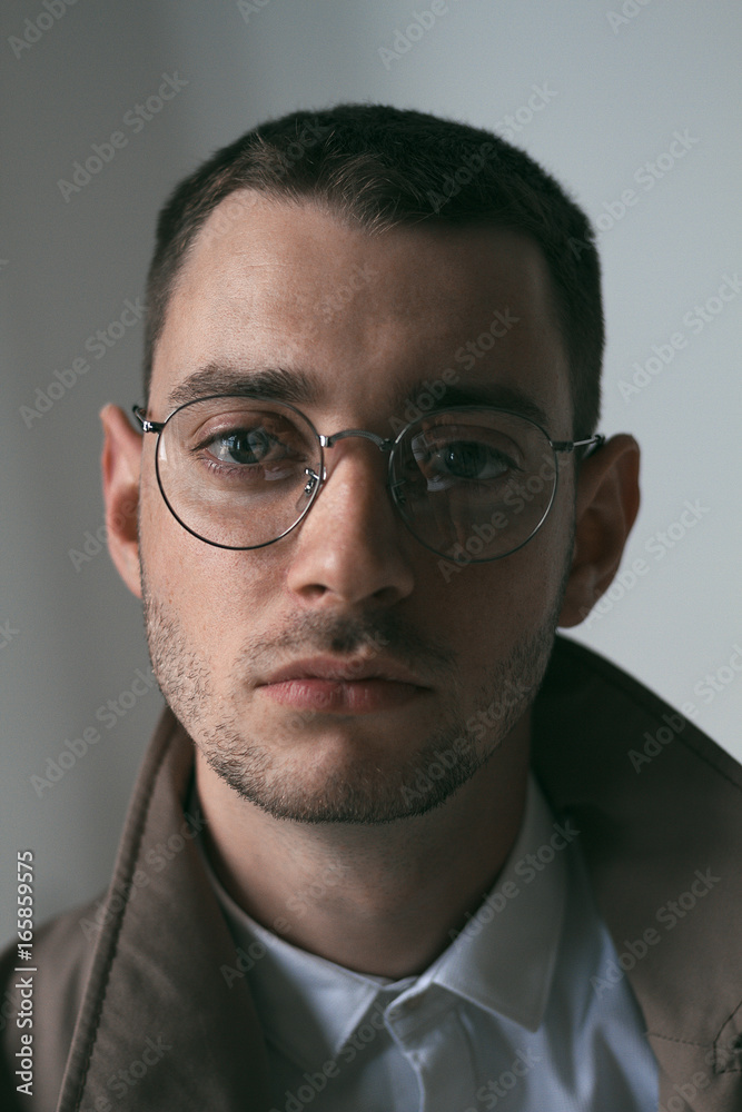 Obraz premium A lonely handsome guy in a raincoat and glasses with different moods