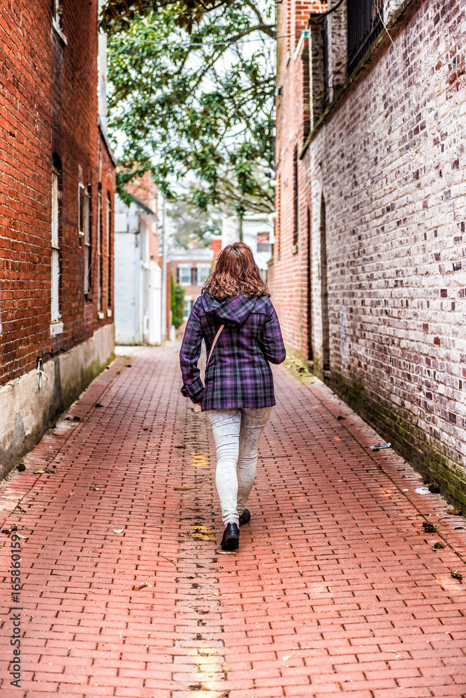 Back on young woman walking in alley way with brick cobblestone in Georgetown neighborhood of Washington DC