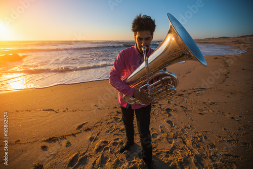 Musician instrumentalist playing the Tuba on the sea coast.