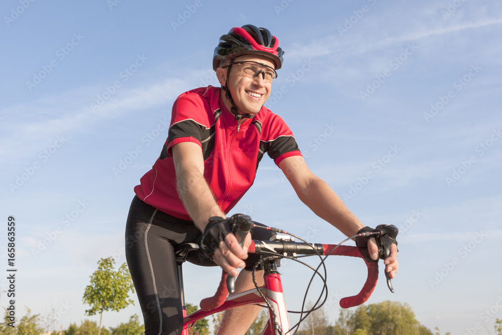 Obraz premium Cycling Concepts. Smiling Professional Road Cyclist During Ride on Bike Outdoors. Completely Equipped in Professional Outfit.