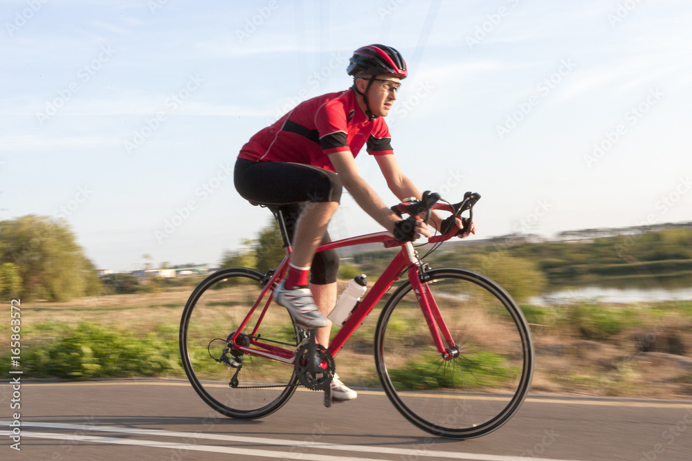 Cycling Concepts. Professional Male Cyclist in Racing Outfit During a Ride on Bike Outdoors. Panning Technique Used.