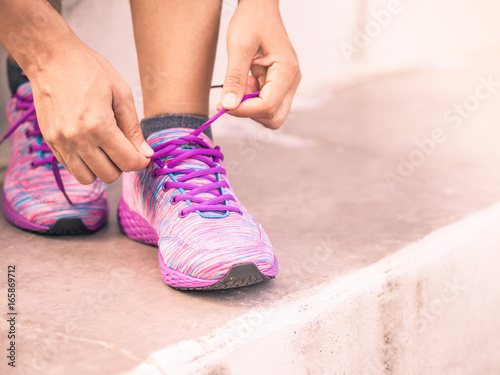 Retro woman tying shoes laces. Closeup of female sport fitness runner getting ready for outdoor jogging. Fitness and sport concept.
