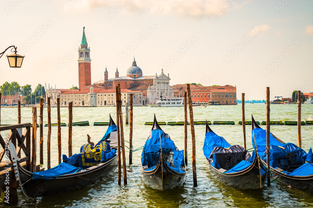 Venice with romantic and famous gondolas moored on grand Canal by San Marco square. 
San Giorgio Maggiore church in the background.
