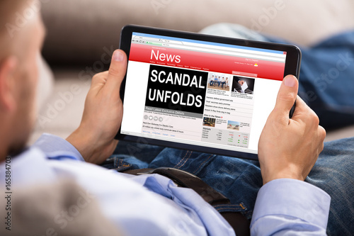 Man Reading Unfolds Scandal News On Digital Tablet photo