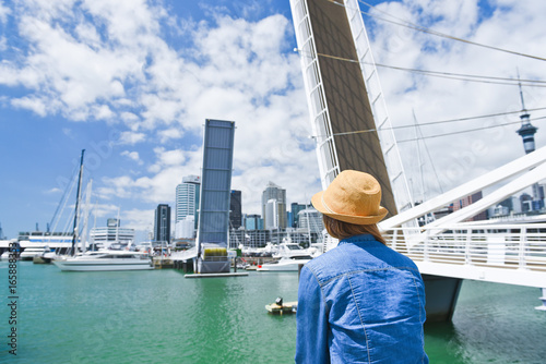 Young traveler woman in hat looking at opening Bridge in Auckland, New Zealand. City life