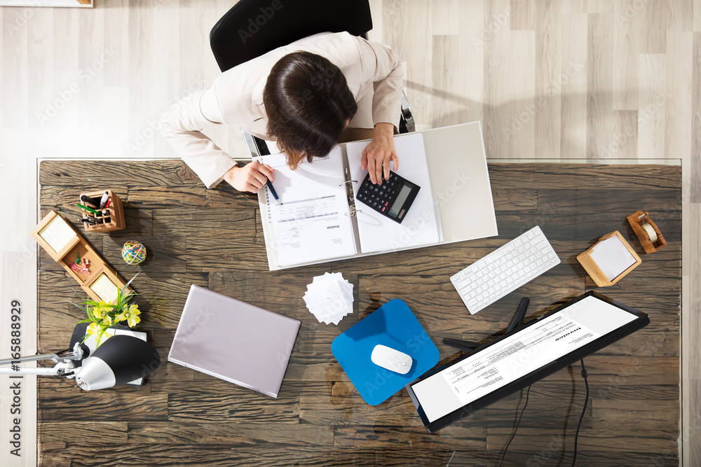 Businesswoman Calculating Invoice In Office