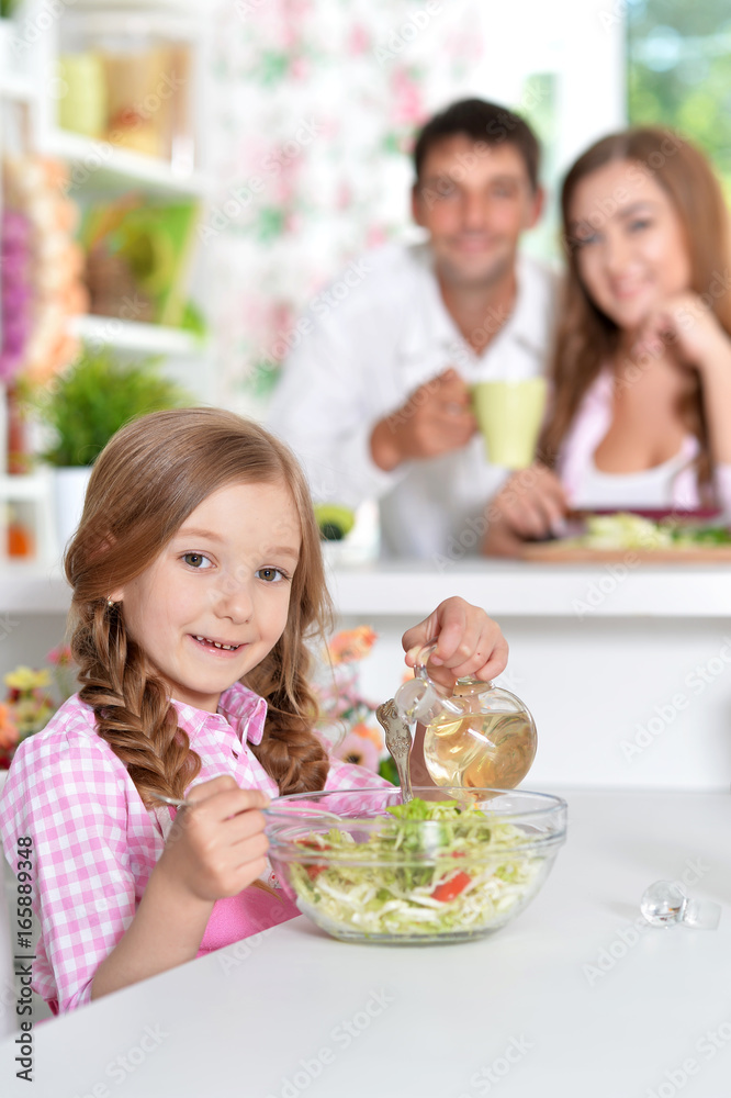 Cute little daughter preparing salad