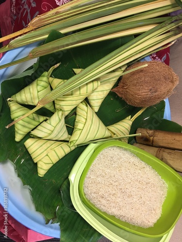 Ketupat (Rice Dumpling), coconut and rice on banana leaves background. Ketupat is a natural rice casing made from young coconut leaves for cooking rice during eid Mubarak