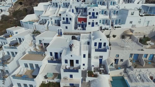 Santorini aerial view video of greek island with white houses and blue roofs on sunset and in the daylight on volcano and sea around the island, aero photo