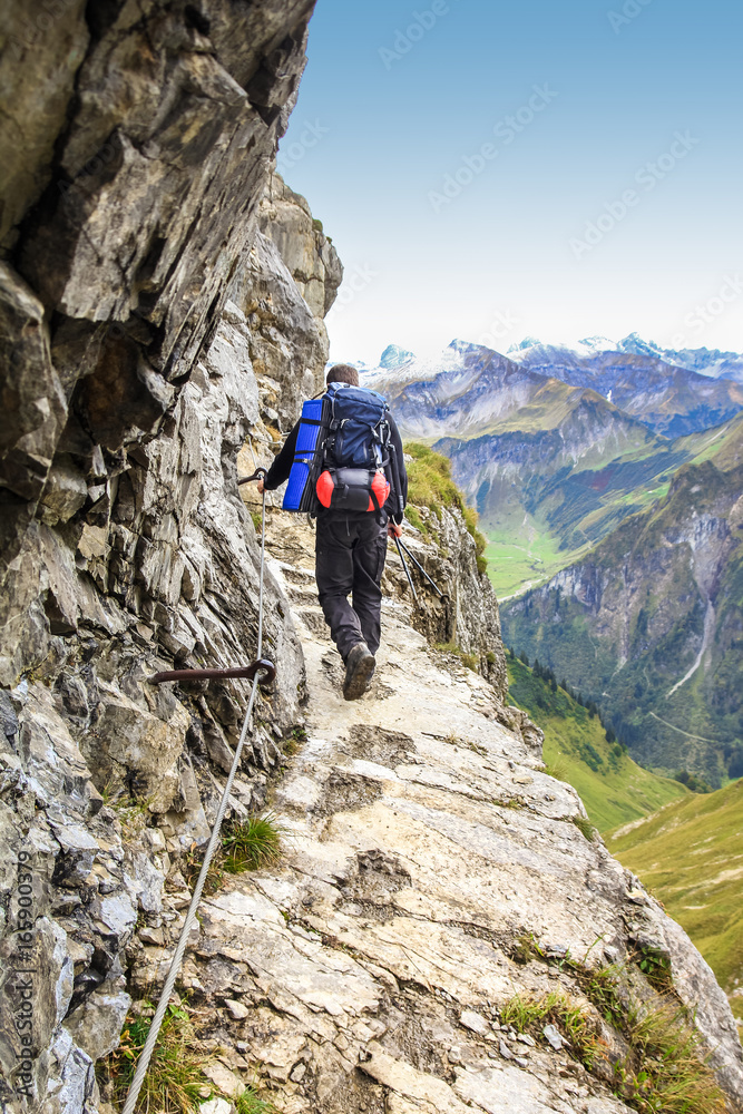 Man walks on dangerous trail in alpine mountains. Alps, Allgau.