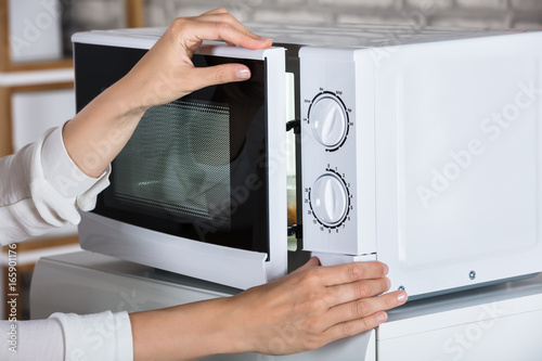 Woman's Hands Closing Microwave Oven Door And Preparing Food