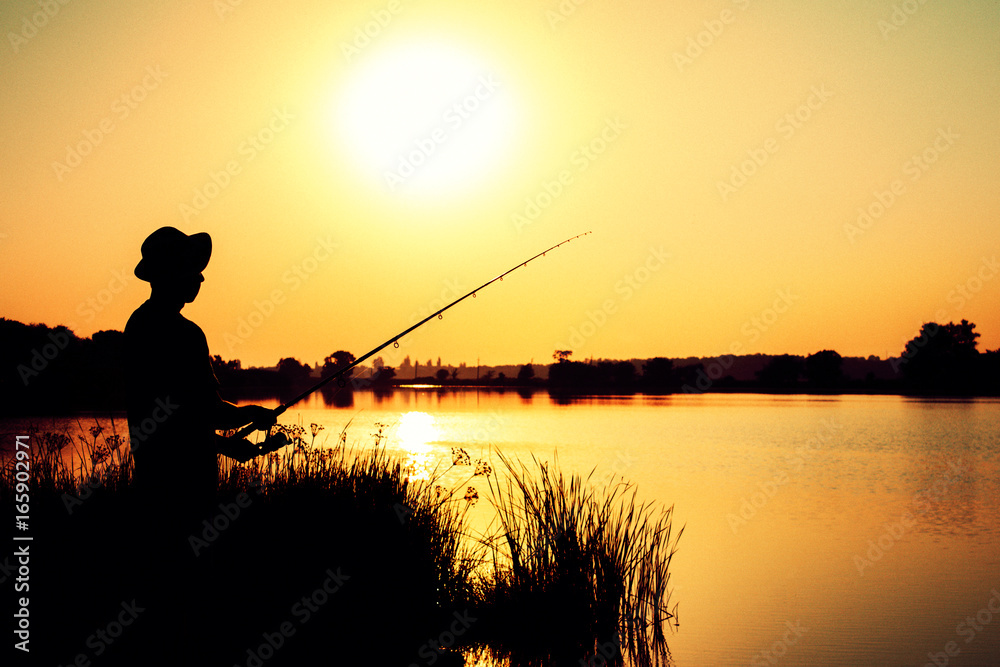 Silhouette of a fishing man on the river bank on the nature