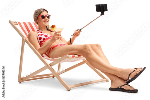 Valokuvatapetti Young woman in a deck chair taking a selfie