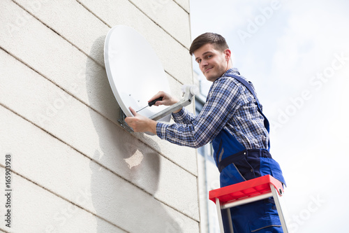 Technician Installing TV Satellite Dish On Wall